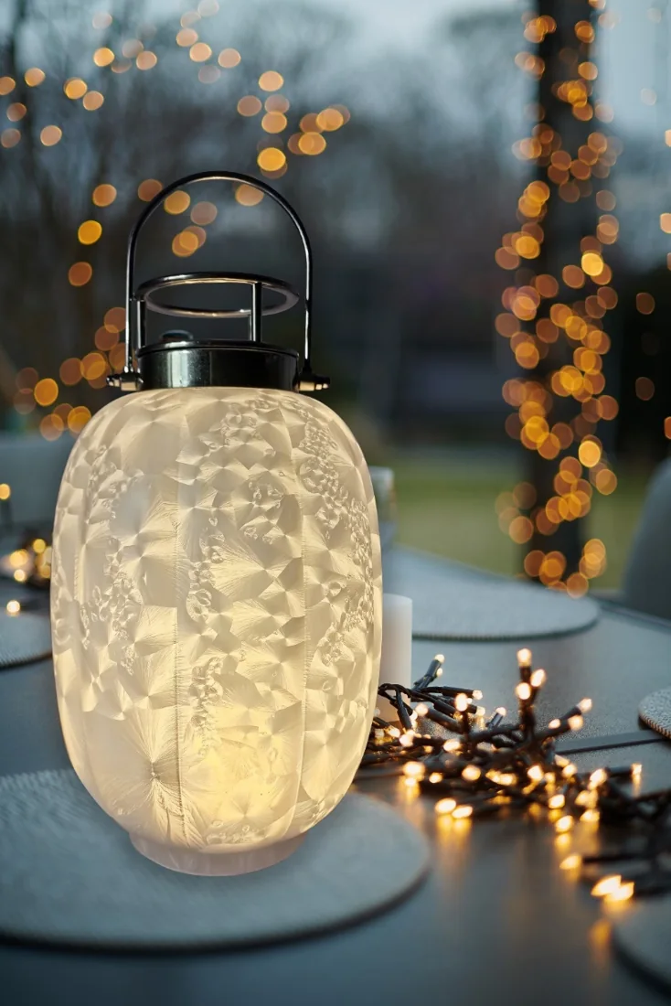 Illuminated frosted glass lantern with a black metal handle