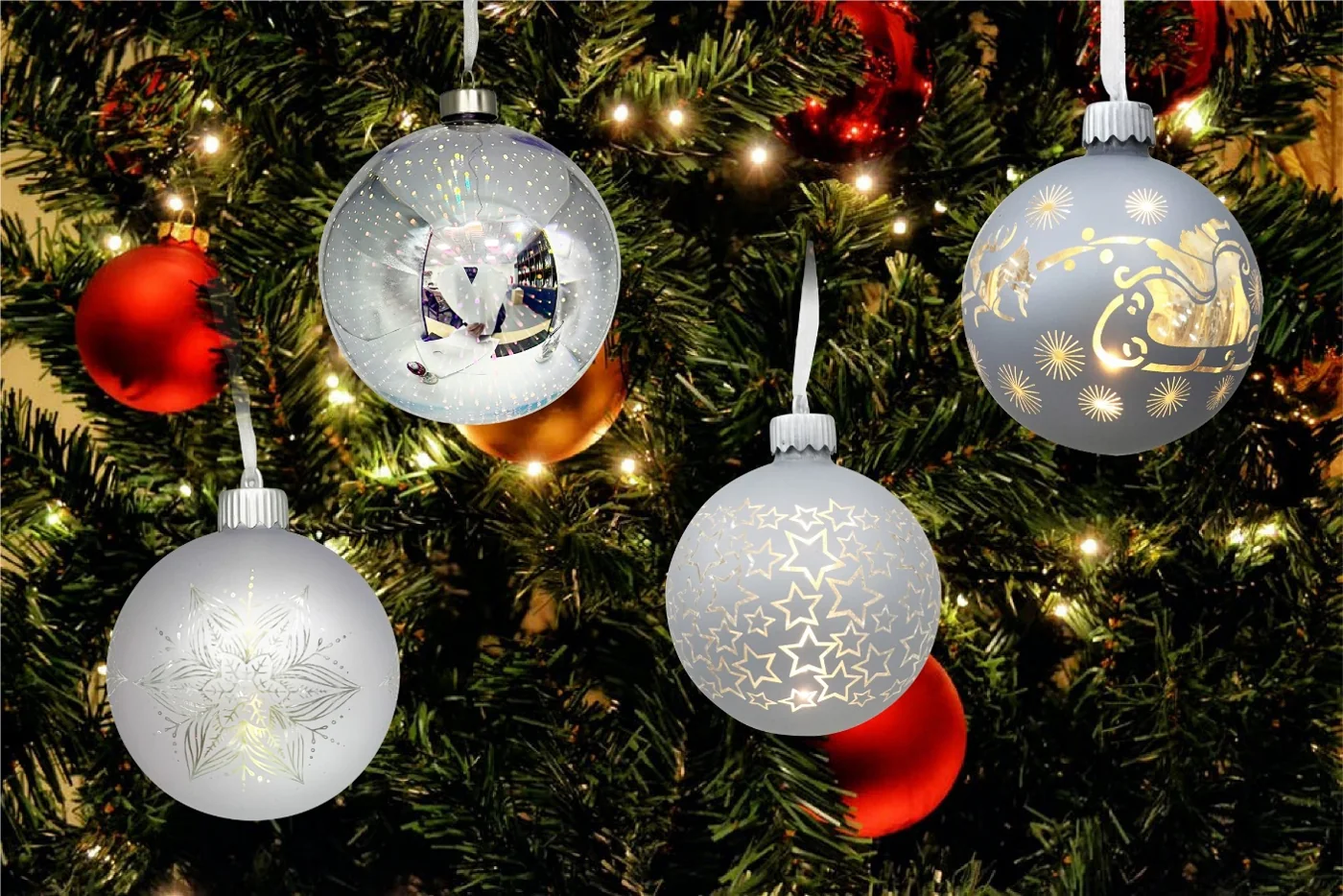 White glass Christmas balls with gold festive printed motifs hanging on a Christmas tree